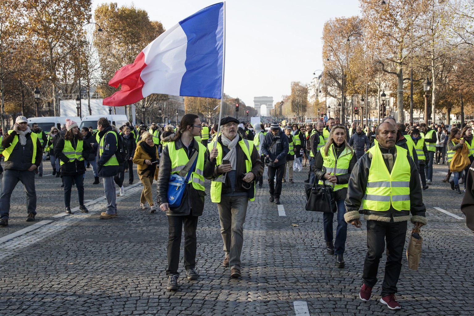 epa07173143 People wearing yellow vests and waving a French flag, as a symbol of French driver&#039;s and citizen&#039;s protest against higher fuel prices, during a demonstration on the Champs Elysee ...