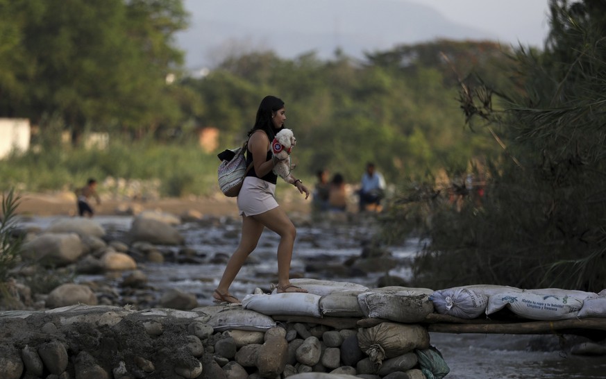 A woman holding her pet crosses illegally into Colombia near the Simon Bolivar International Bridge in La Parada near Cucuta, Colombia, Wednesday, May 1, 2019, on the border with Venezuela. The border ...