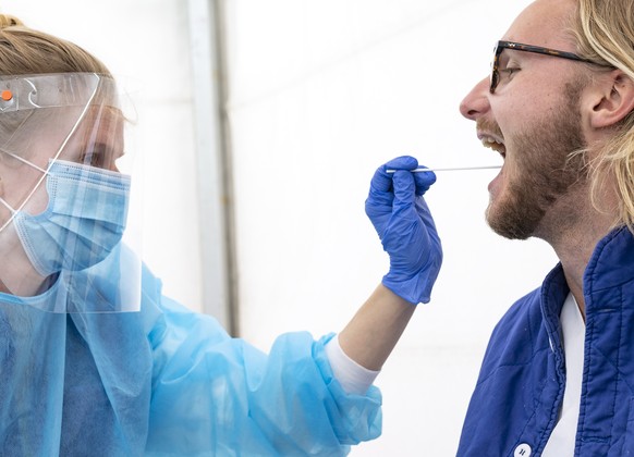 epa08391751 Medical staff in protective gear administer a Covid-19 test at a test facility in a tent outside Skane University Hospital in Lund, Sweden, 29 April 2020. The Skane region this week starte ...