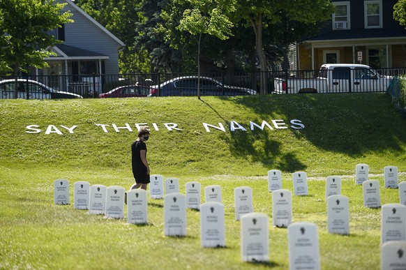 epaselect epa08473926 A man walks through a make shift cemetery with the names of people killed by police officers near the intersection of 38th and Chicago in front of the Cup Foods at the spot where ...