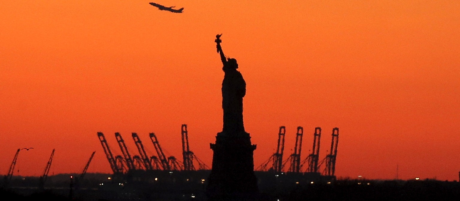 FILE PHOTO - A plane is seen during take off in New Jersey behind the Statue of Liberty in New York&#039;s Harbor as seen from the Brooklyn borough of New York February 20, 2016. REUTERS/Brendan McDer ...