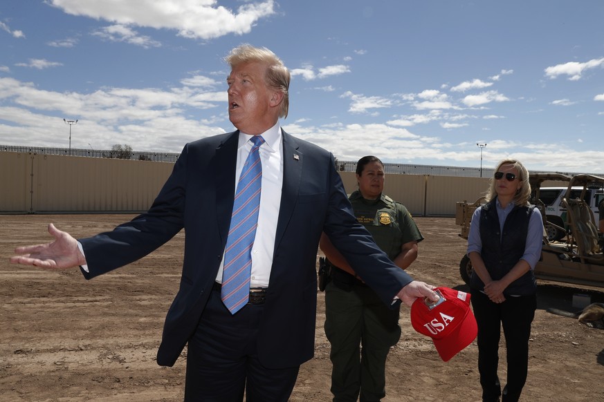 President Donald Trump visits a new section of the border wall with Mexico in Calexico, Calif., Friday April 5, 2019. Gloria Chavez with the U.S. Border Patrol, center, and Homeland Security Secretary ...