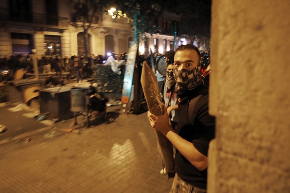 A protestors holding a wooden stake looks from behind a street corner during clashes with police in Barcelona, Spain, Thursday, Oct. 17, 2019. Catalonia&#039;s separatist leader vowed Thursday to hold ...