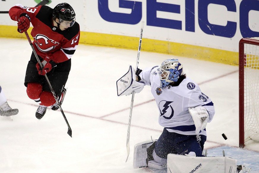 New Jersey Devils center Nico Hischier, left, of Switzerland, jumps out to screen a shot from a teammate as Tampa Bay Lightning goalie Peter Budaj, of Slovakia, (31) deflects the shot during the third ...
