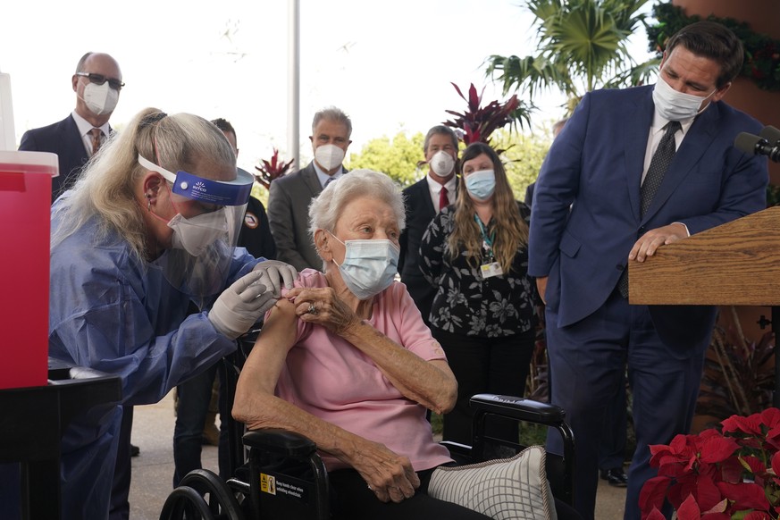 FILE- In this Dec. 16, 2020, file photo, Florida Gov. Ron DeSantis watches as nurse Christine Philips, left, administered the Pfizer vaccine to resident Vera Leip, 88, at John Knox Village, in Pompano ...