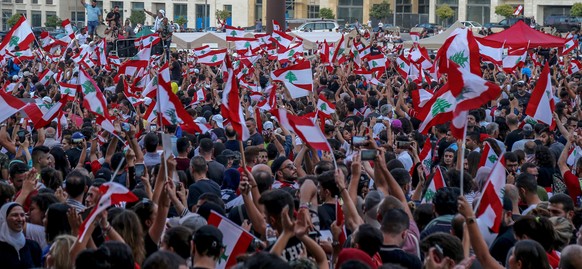 epa07934646 Protesters wave Lebanese flags and shout anti-government slogans during a protest in front the Government palace in downtown Beirut, Lebanon, 19 October 2019. Hundreds of thousands of Leba ...