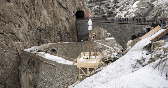 epa09144605 The Boeoegg, a symbolic snowman, is lowered by a large crane onto the platform over the Devil&#039;s Bridge, in the Schoellenen Gorge near Andermatt, Switzerland, 19 April 2021. The Sechse ...