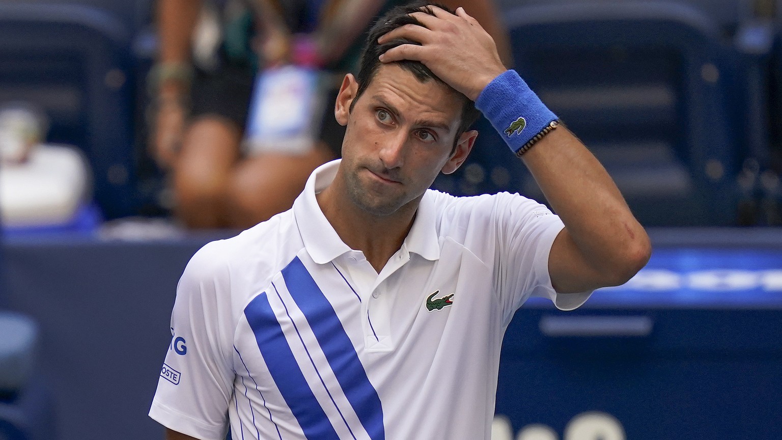 Novak Djokovic, of Serbia, reacts after inadvertently hitting a line judge with a ball after hitting it in reaction to losing a point against Pablo Carreno Busta, of Spain, during the fourth round of  ...
