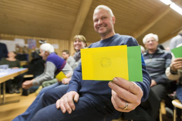 epa06359991 A resident of Albinen shows his voting card, during the communal assembly of Albinen, in Albinen, Switzerland, 30 November 2017. The residents of Albinen will vote on a new communal regula ...