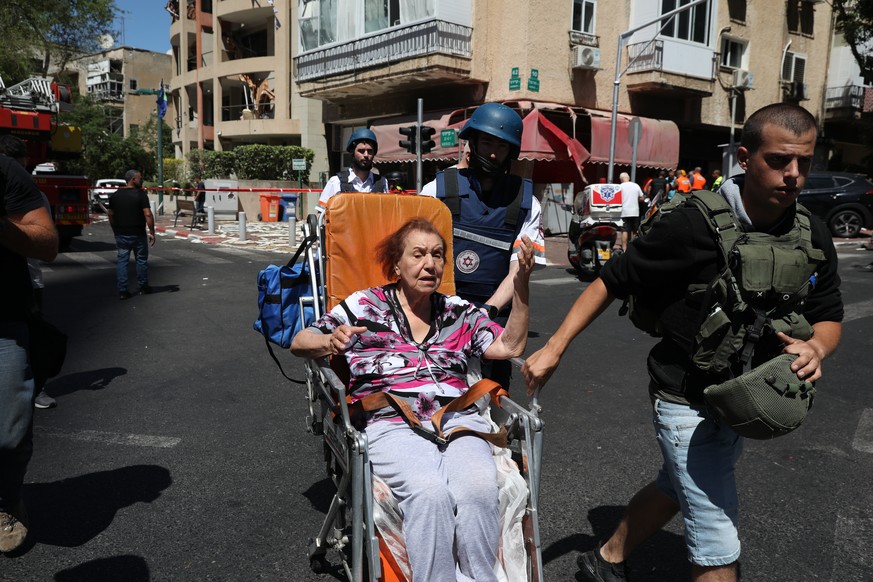 epa09201312 An Israeli emergency team evacuates a woman at the scene where a rocket fired from the Gaza Strip hit in the central city of Ramat Gan near Tel Aviv, Israel, 15 May 2021. In response to da ...