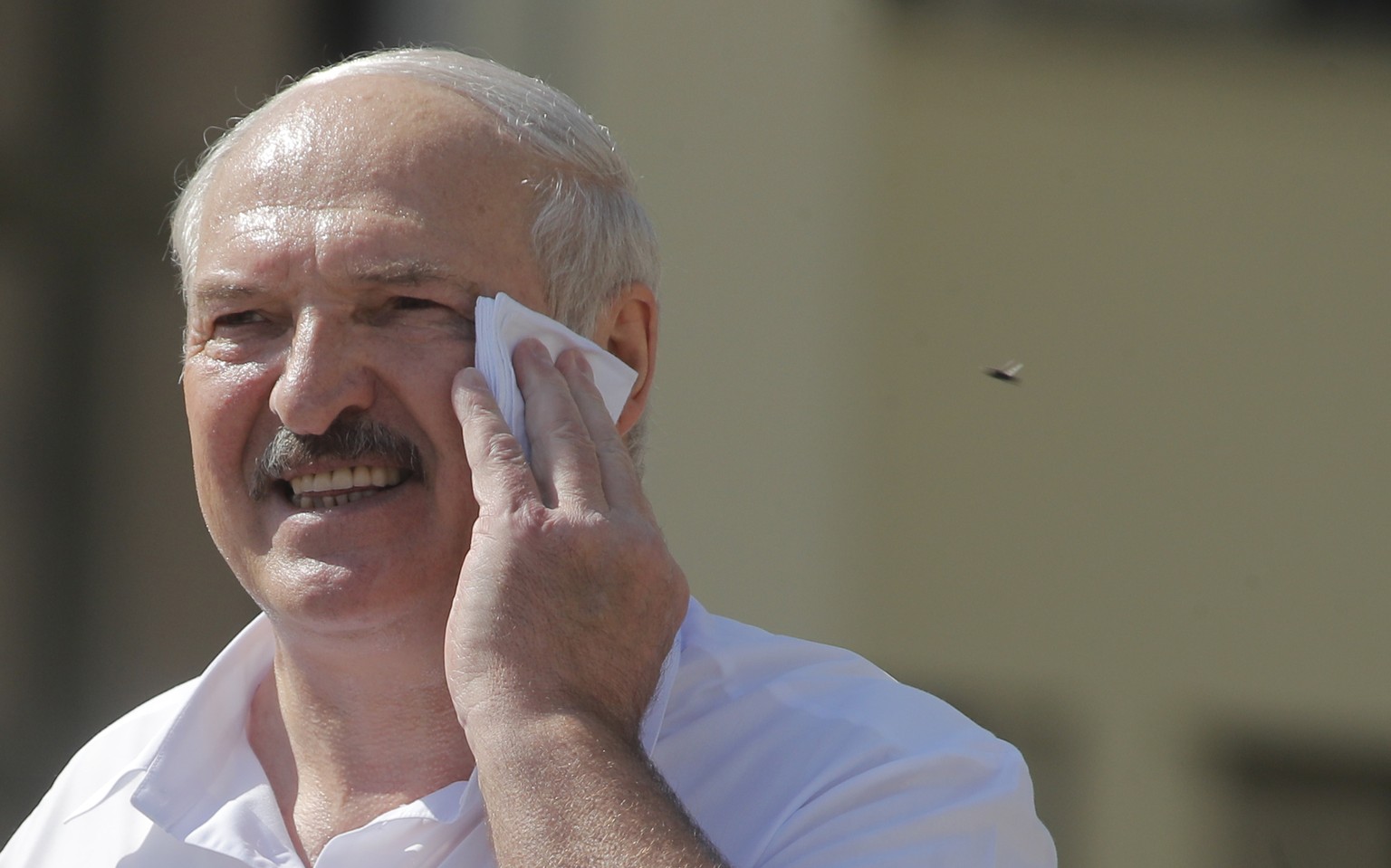 Belarusian President Alexander Lukashenko wipes his face as he addresses his supporters gathered at Independent Square of Minsk, Belarus, Sunday, Aug. 16, 2020. Thousands of people have gathered in a  ...