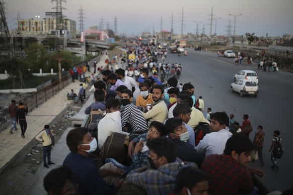 Indian migrant workers sit atop a bus, provided by the government, as others walk along an expressway to their villages following a lockdown amid concern over spread of coronavirus in New Delhi, India ...