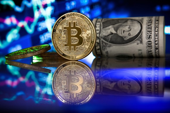 epa09017765 (FILE) - A bitcoin in front of a monitor showing a stock barometer in Duesseldorf, Germany, 20 January 2021 (reissued 17 February 2021). Cryptocurrency Bitcoin&#039;s value value crossed t ...