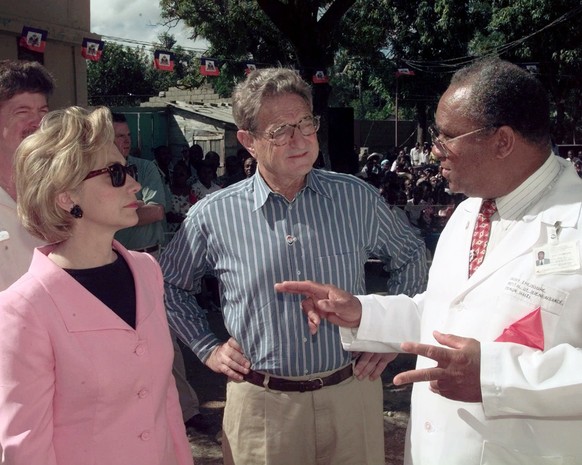 FILE - U.S. first lady Hillary Clinton and international financier and philanthropist George Soros listen as Dr. Guy Theodore, founder and director of the Well Being Hospital in Pignon, Haiti, explain ...