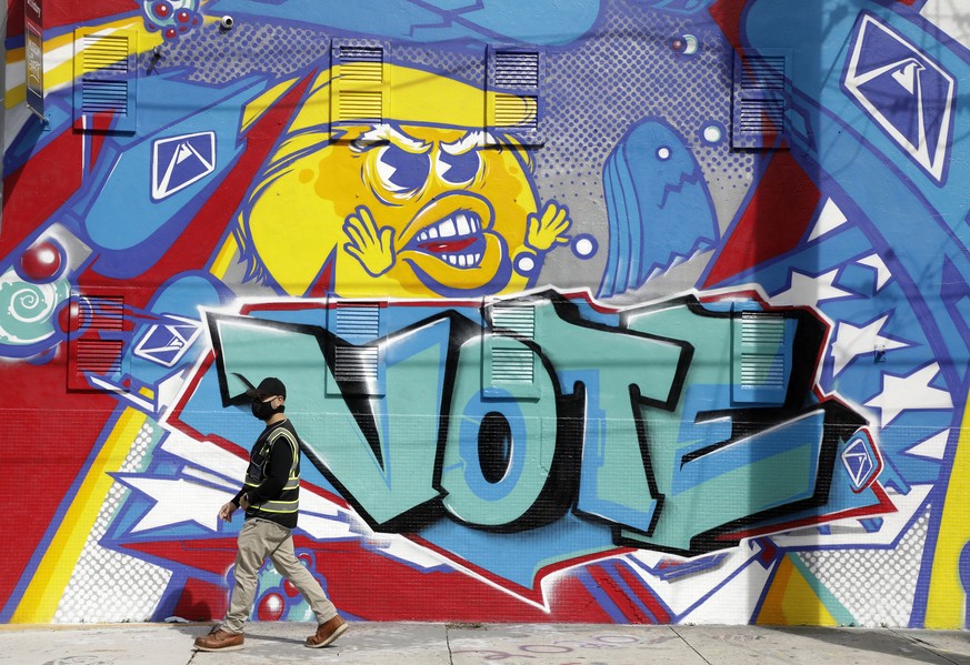 epaselect epa08797059 A man walks by a vote mural in the Wynwood neighborhood of Miami, Florida, USA, 03 November 2020. Americans vote on Election Day to choose between re-electing Donald J. Trump or  ...