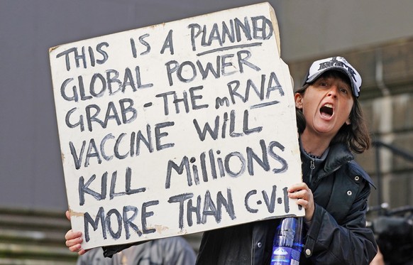 epa08412637 A protester holds aup a banner as they gather outside Parliament House in Melbourne, Victoria, Australia, 10 May 2020, during the coronavirus disease (COVID-19) pandemic. Anti-vaxxers and  ...