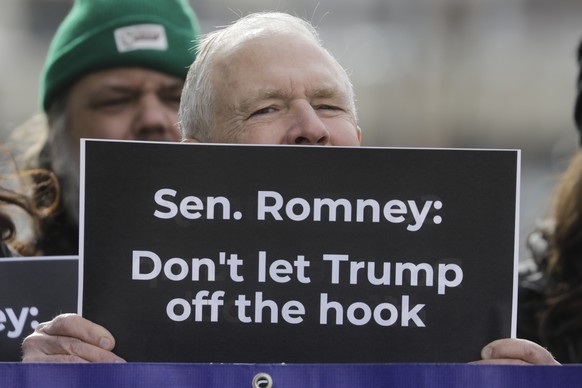 FILE - In this Jan. 16, 2020, file photo, Scott Riching joins others outside the office of Sen. Mitt Romney to call on him to push for a full and fair impeachment trial in the Senate with pertinent te ...