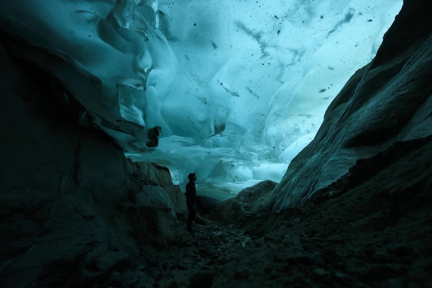 epa08416305 A man watches the ice in an ice cave in the Swiss Aletsch Glacier, in Valais, Switzerland, 25 September 2019 (reissued 12 May 2020). Turquoise, originally the French word for &#039;Turkish ...