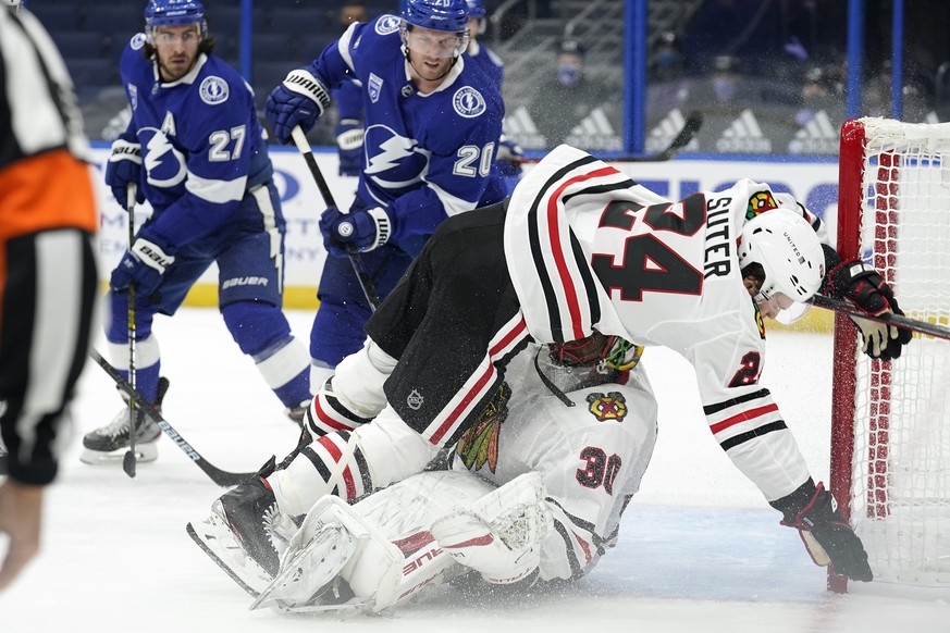 Chicago Blackhawks center Pius Suter (24) falls on goaltender Malcolm Subban (30) after a check by Tampa Bay Lightning center Blake Coleman (20) during the second period of an NHL hockey game Wednesda ...