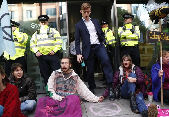 A man walks out of the Home office past climate change protesters on the second day of ongoing protests in London, Tuesday, Oct. 8, 2019. Police are reporting they have arrested more than 300 people a ...