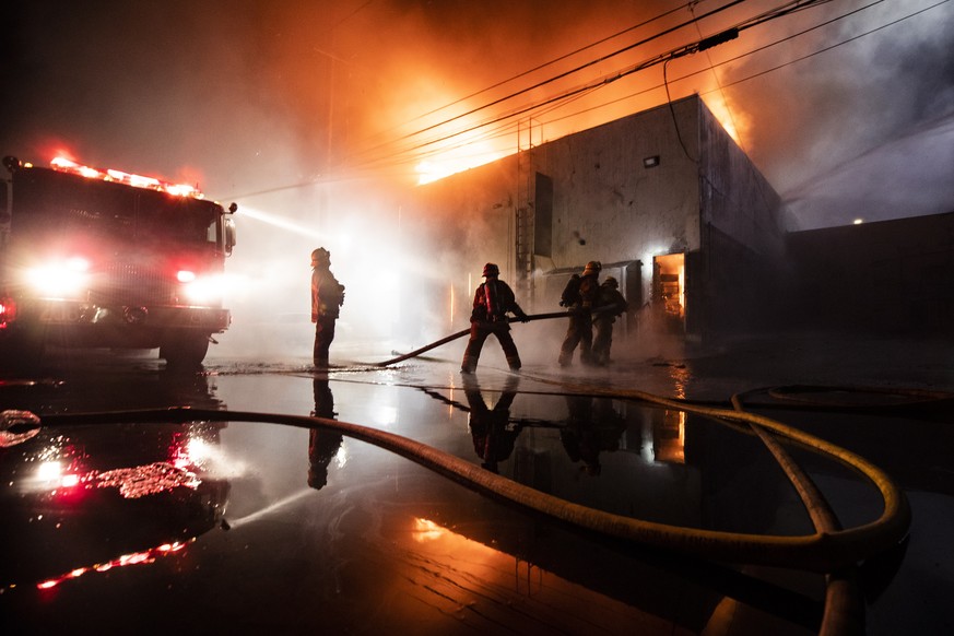 epa08455595 Firefighters put out a fire in a looted store set on fire on Melrose during curfew as thousands of protesters take the street to demonstrate following the death of George Floyd, in Los Ang ...