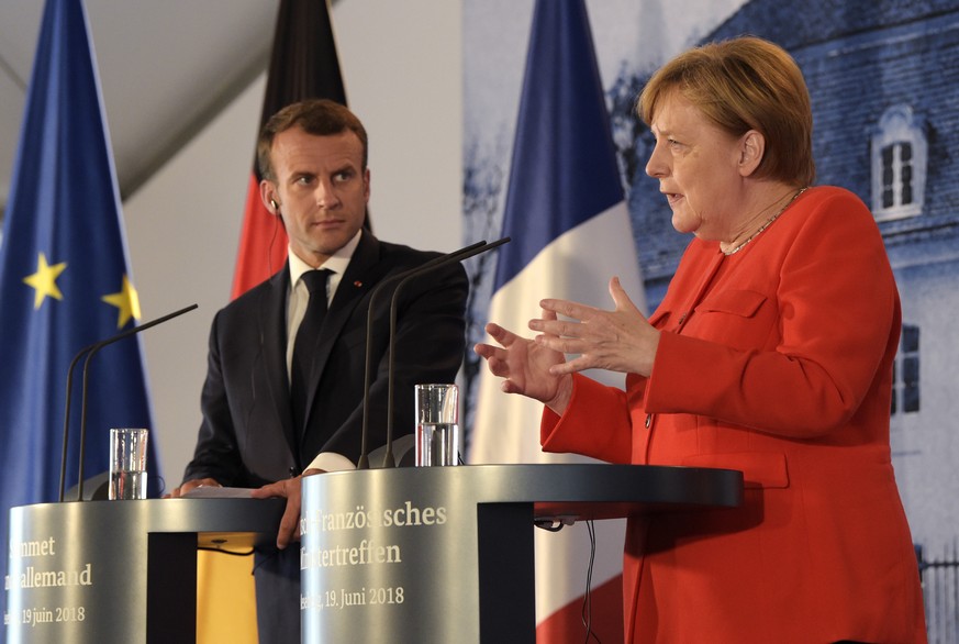 France&#039;s President Emmanuel Macron, left, listens to German Chancellor Angela Merkel at a press conference after a meeting in the guest house of the German government in Meseberg north of Berlin, ...