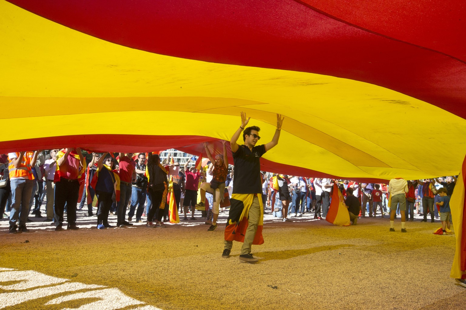 A youth walks under a giant Spanish flag in Madrid, Spain, Saturday, Oct. 7, 2017. Thousands of pro-Spanish unity supporters donning Spanish flags have rallied in a central Madrid plaza to protest the ...