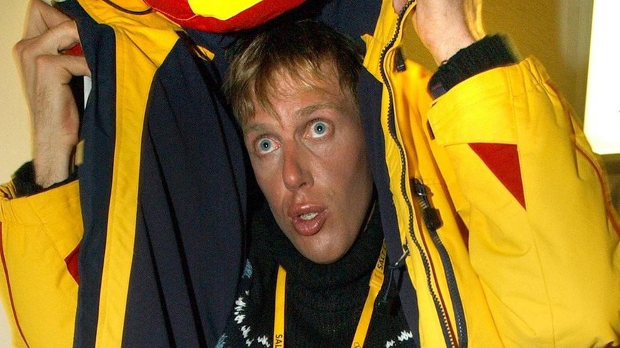 Cross country skier Johann Muehlegg takes cover from photographers as he arrives for a television interview in Salt Lake City February 24, 2002. The IOC announced that Muehlegg had been found guilty o ...
