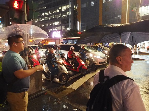 epa07762252 Two men wait to cross the street during a shower brought by Typhoon Lekima in Taipei, Taiwan, 08 August 2019. According to the Central Weather Bureau, Strong Typhoon Lekima will bring heav ...