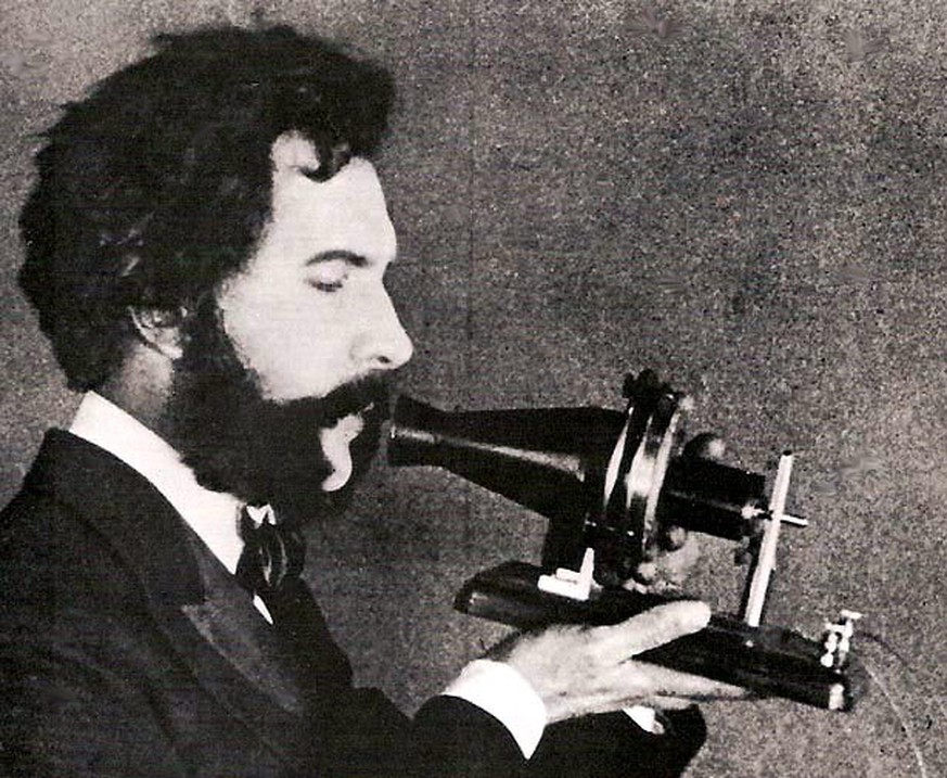 Ein Schauspieler in der Rolle von Alexander Graham Bell spricht in ein Telefon.