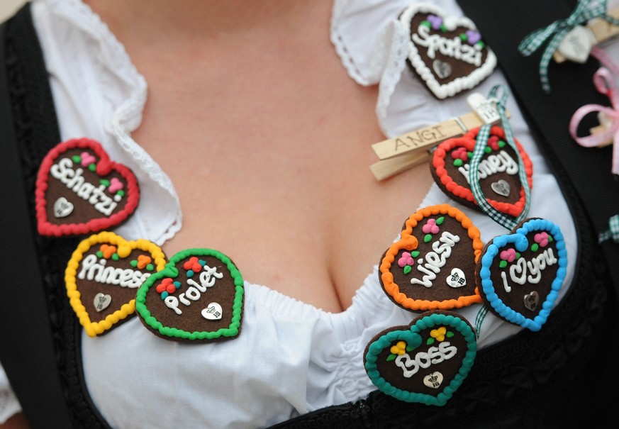 A seller wears bagdes in the shape of gingerbread hearts on the neckline of her dirndl dress during the opening of the traditional Bavarian Oktoberfest festival at the Theresienwiese in Munich, southe ...