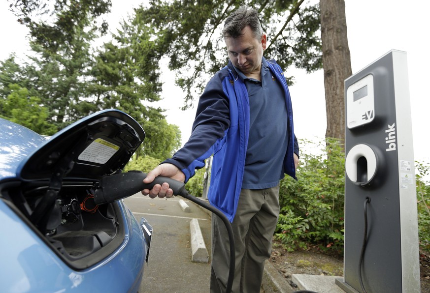 Patrick Conner&#039; shows how to plug his Nissan Leaf electric car at a charging station at the public library in Hillsboro, Ore., Tuesday, May 19, 2015. Fuel-efficient, hybrid and electric cars are  ...
