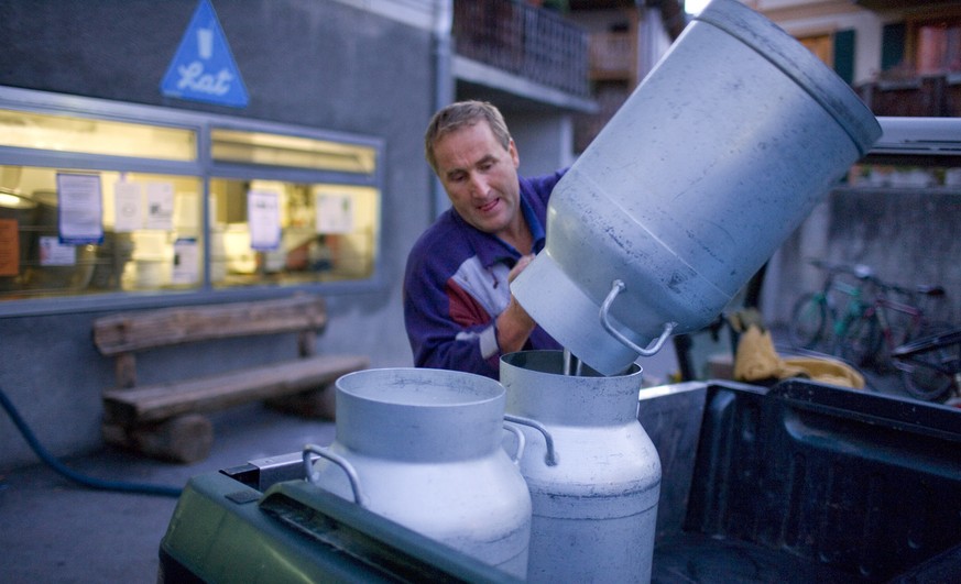 Ein Bauer leert vor der Molkerei in Sent im Engadin, Kanton Graubuenden, Schweiz, seine Milchkannen um, aufgenommen am 16. Oktober 2006. (KEYSTONE/Martin Ruetschi) === , ===

A farmer empties his milk ...