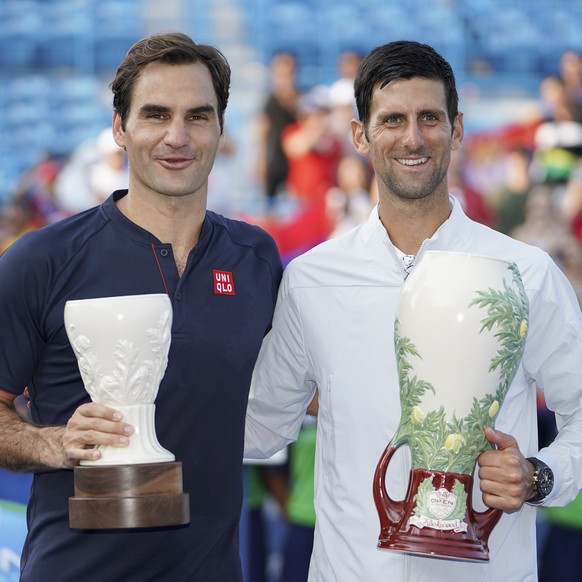 Novak Djokovic, right, of Serbia, holds the Rookwood Cup after defeating Roger Federer, left, of Switzerland, during the finals at the Western &amp; Southern Open tennis tournament, Sunday, Aug. 19, 2 ...