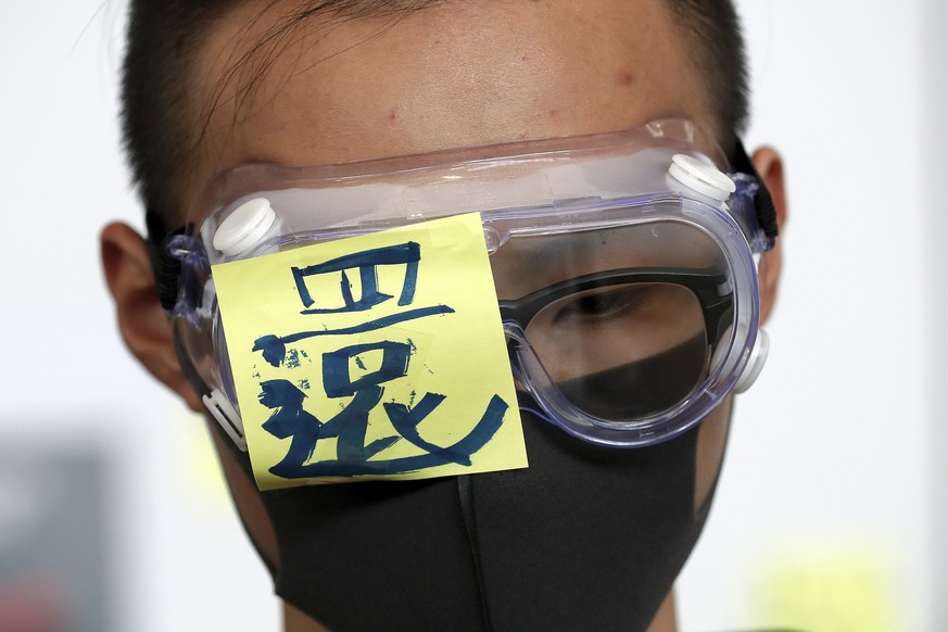 A protester wears a goggle with a word &quot;Return&quot; during a protest at the arrival hall of the Hong Kong International Airport in Hong Kong Monday, Aug. 12, 2019. It is reported that police sho ...