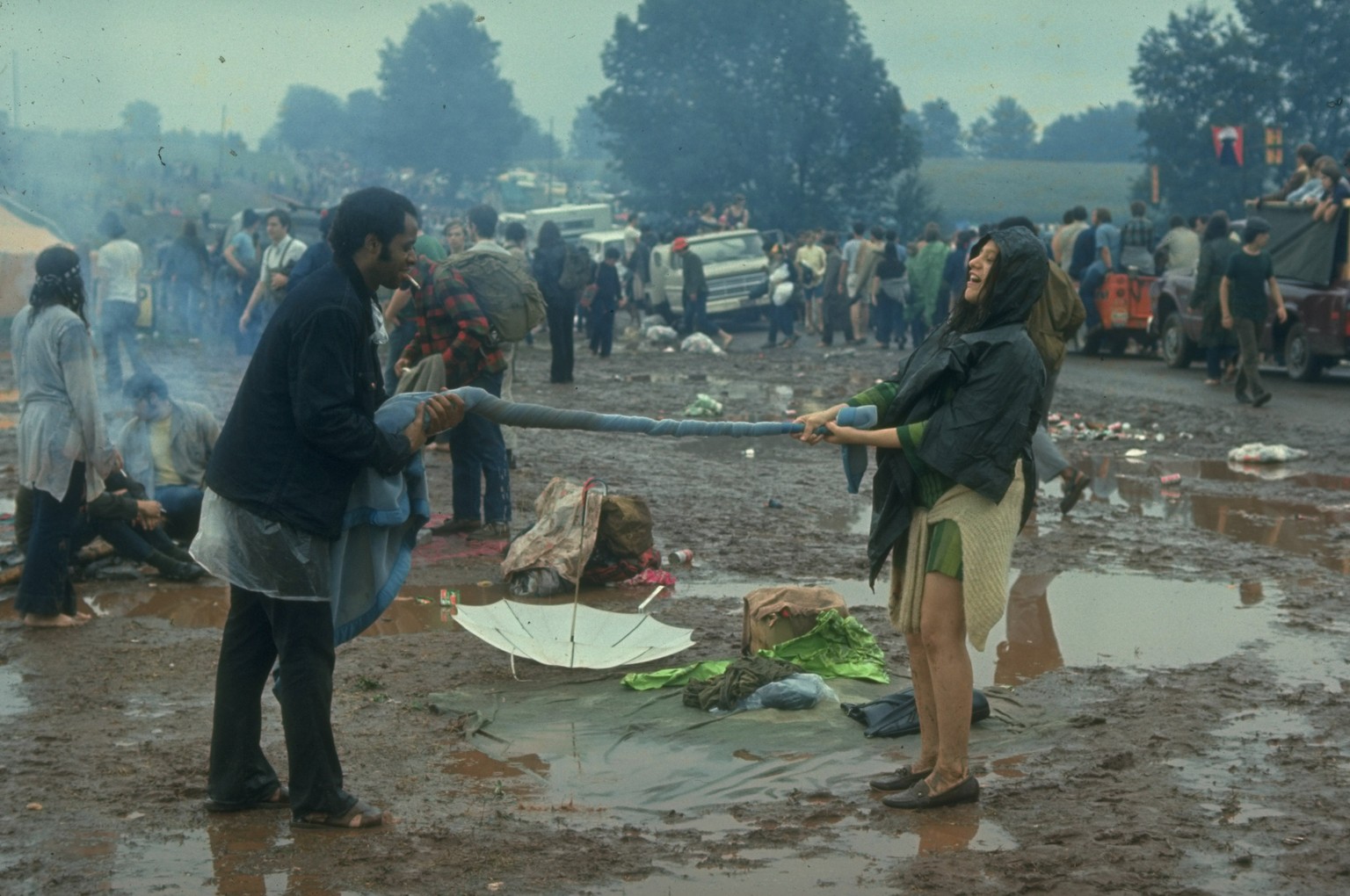NEW YORK, UNITED STATES - AUGUST 1969: Couple twisting a blanket between them, probably trying to squeeze out the water, during the Woodstock Music &amp; Art Fair. (Photo by John Dominis/The LIFE Pict ...