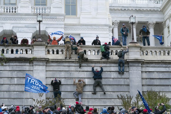 FILE - In this Jan. 6, 2021, file photo violent insurrectionists loyal to President Donald Trump climb the west wall of the the U.S. Capitol in Washington. A month ago, the U.S. Capitol was besieged b ...