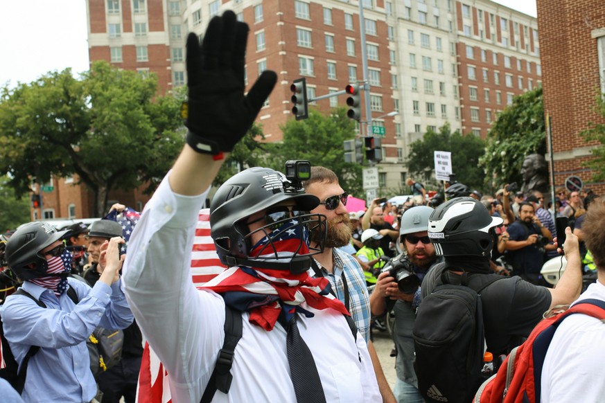 Washington, D.C., USA. 12 Aug 2018. White nationalist protestors headed to the Unite the Right protest are escorted through the streets of Washington, D.C. by police as counterprotestors look on.