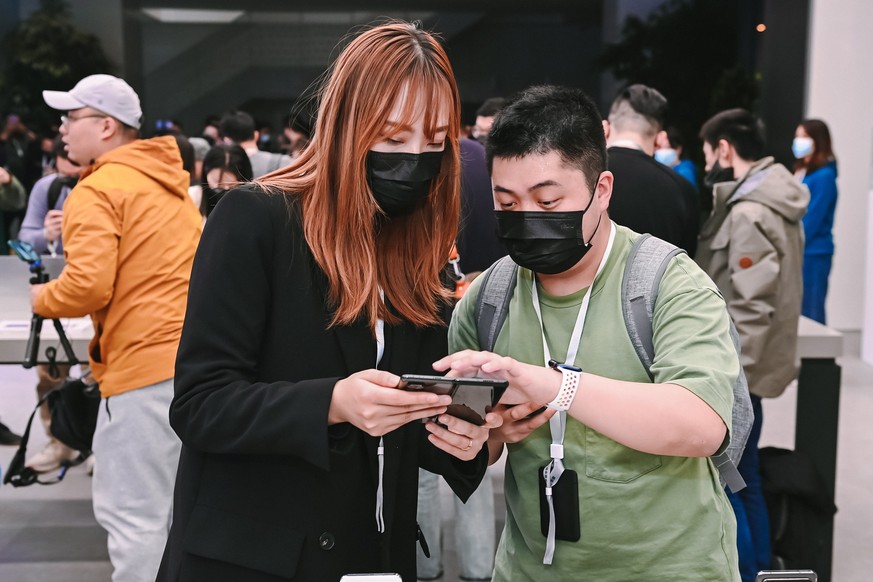 epa09107936 A handout photo made available by Xiaomi on 31 March 2021 shows people looking at Xiaomi&#039;s new foldable smartphone Mi Mix Fold during the new products unveiling event in Beijing, Chin ...