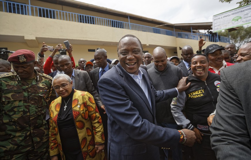Kenya&#039;s President Uhuru Kenyatta, center, shakes hands with supporters, accompanied by his wife Margaret, center-left, after casting his vote in Gatundu, north of Nairobi, in Kenya Tuesday, Aug.  ...