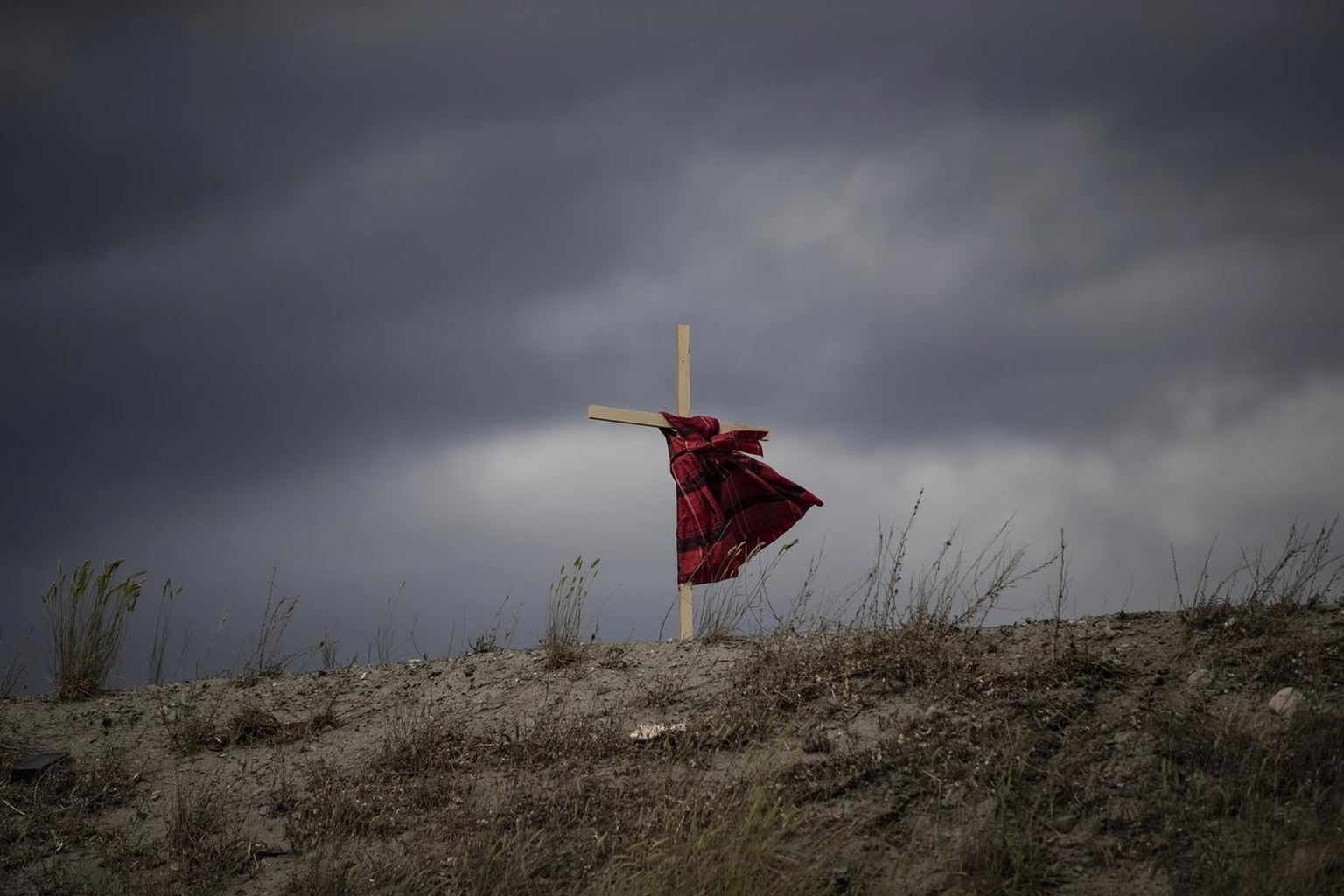 A child&#039;s dress hangs on a cross as it blows in the wind near the former Kamloops Indian Residential School, to honor the 215 children whose remains have been discovered buried near the facility  ...
