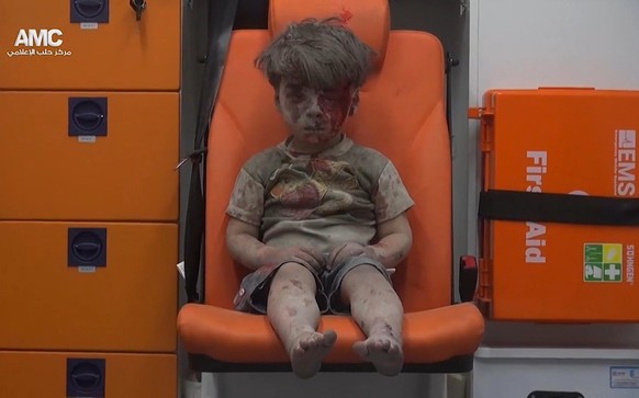 FILE - In this frame grab taken from video provided by the Syrian anti-government activist group Aleppo Media Center (AMC), 5-year-old Omran Daqneesh sits in an ambulance after being pulled out or a b ...