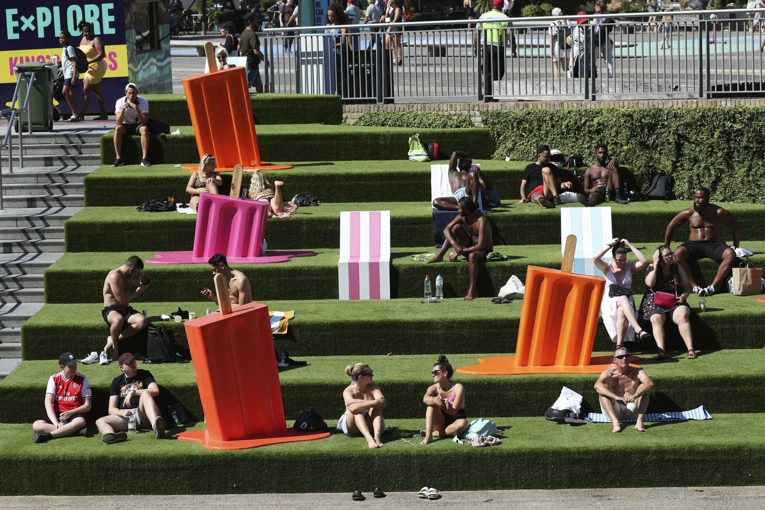 People sunbathe on the steps near Granary Square, King&#039;s Cross, as the warm weather continues, in London, Friday, Aug. 7, 2020. The UK could see record-breaking temperatures with forecasters pred ...