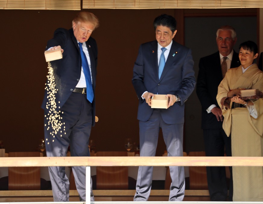 President Donald Trump feeds Koi fish as Japan Prime Minister Shinzo Abe, center, and Secretary of State Rex Tillerson second from right, watch during a stop at a Koi pond during a visit to the Akasak ...