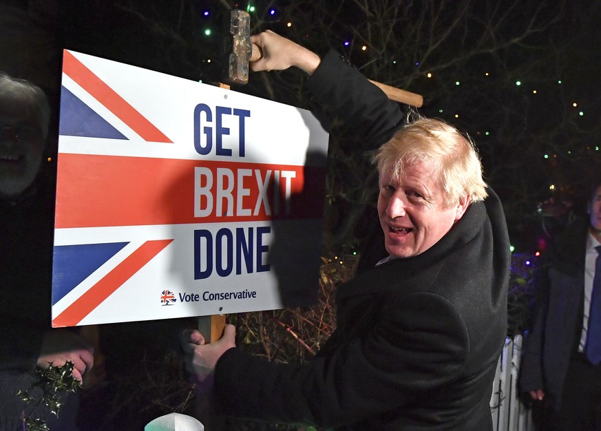 FILE -- In this Wednesday, Dec. 11, 2019 file photo, Britain&#039;s Prime Minister and Conservative party leader Boris Johnson poses as he hammers a &quot;Get Brexit Done&quot; sign into the garden of ...