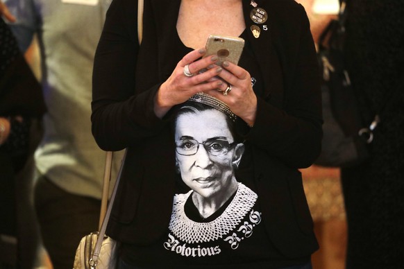 Laura Taylor wears a shirt with a likeness of U.S. Supreme Court justice Ruth Bader Ginsburg as she checks returns at an election night party for Democrats Tuesday, Nov. 6, 2018, in Bellevue, Wash. (A ...