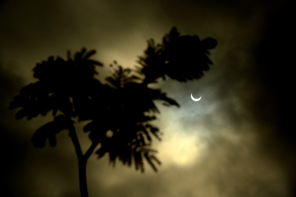 epa08090267 A solar eclipse is visible through cloud cover in Mysore, India on 26 December 2019. The rare and unusual celestial annular solar eclipse, the moon covers the Sun&#039;s centre, leaving th ...