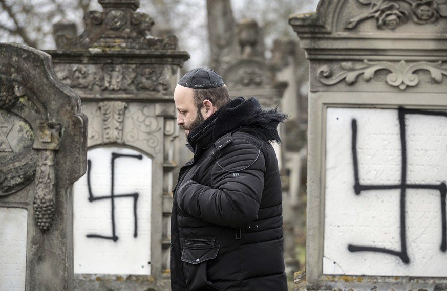 A member of the Jewish community walks among defaced gravestones at the Jewish cemetery of Herrlisheim, near Strasbourg, eastern France, Friday, Dec.14, 2018. 37 gravestones and a monument for Holocau ...
