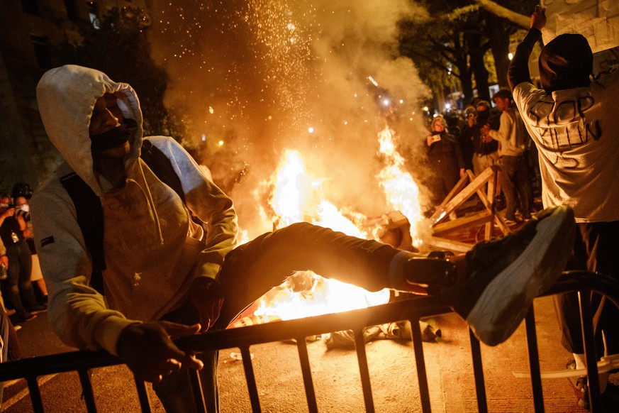 epa08457260 A protester shows off his ankle bracelet next to a fire during a demonstration over the death of George Floyd, who died in police custody, near the White House in Washington, DC, USA, 31 M ...