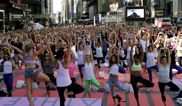 epa04270961 Men and women practice power yoga to celebrate the summer solstice in Time Square in New York, New York, USA, 21 June 2014. EPA/PETER FOLEY